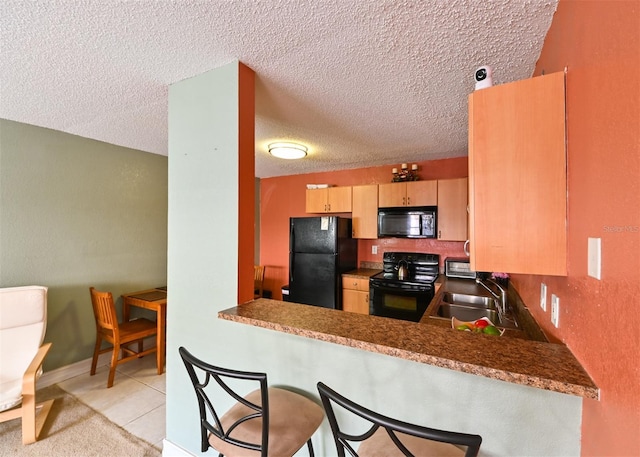 4015 My Lady Ln Unit 7, Land O Lakes, FL 34638 - kitchen with black appliances, a textured ceiling, a peninsula, a breakfast bar, and light brown cabinets