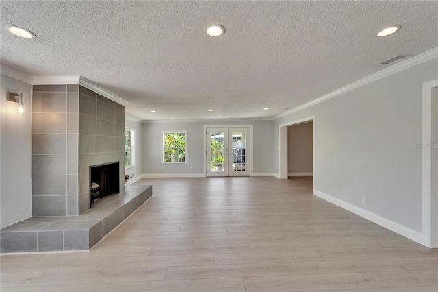 4518 Helena St NE, Saint Petersburg, FL 33703 - unfurnished living room with ornamental molding, a textured ceiling, light wood-style floors, recessed lighting, and a tiled fireplace