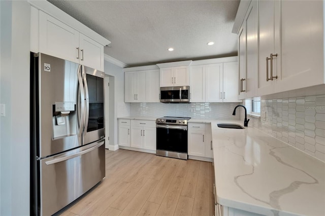 4518 Helena St NE, Saint Petersburg, FL 33703 - kitchen featuring stainless steel appliances, light wood finished floors, white cabinetry, light stone counters, and recessed lighting