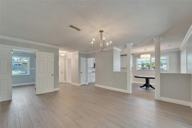 4518 Helena St NE, Saint Petersburg, FL 33703 - unfurnished living room with crown molding, a chandelier, light wood-style floors, a textured ceiling, and ornate columns