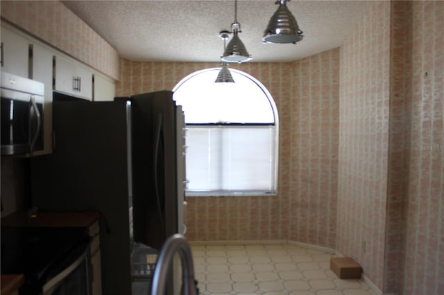 5581 Greyston St, Palm Harbor, FL 34685 - kitchen featuring wallpapered walls, stainless steel microwave, black range with electric stovetop, light floors, and a textured ceiling