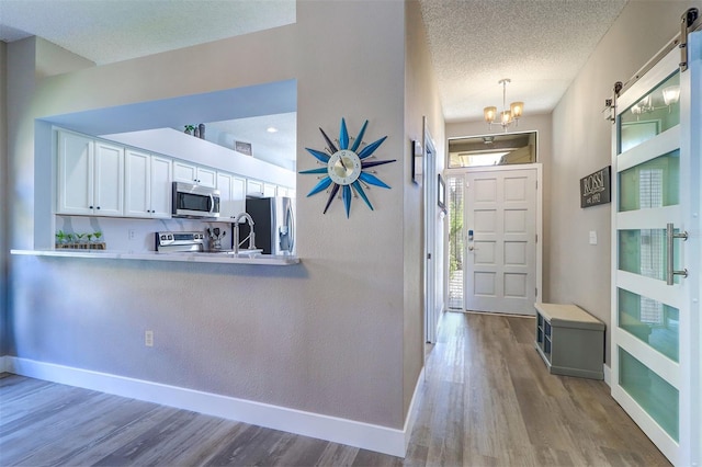 3704 Darston St, Palm Harbor, FL 34685 - foyer entrance featuring wood finished floors, a textured ceiling, a chandelier, and a barn door