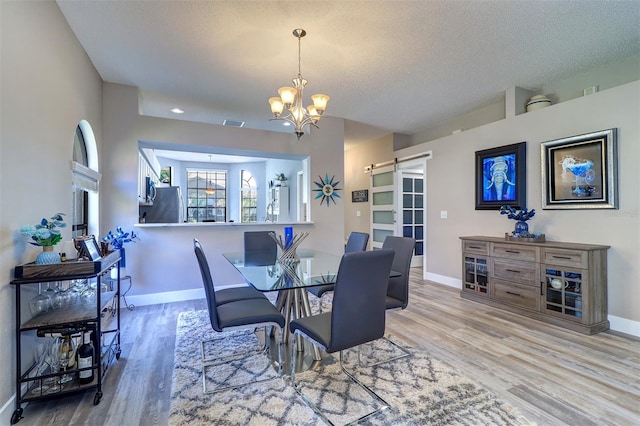 3704 Darston St, Palm Harbor, FL 34685 - dining room with a chandelier, a barn door, wood finished floors, and a textured ceiling