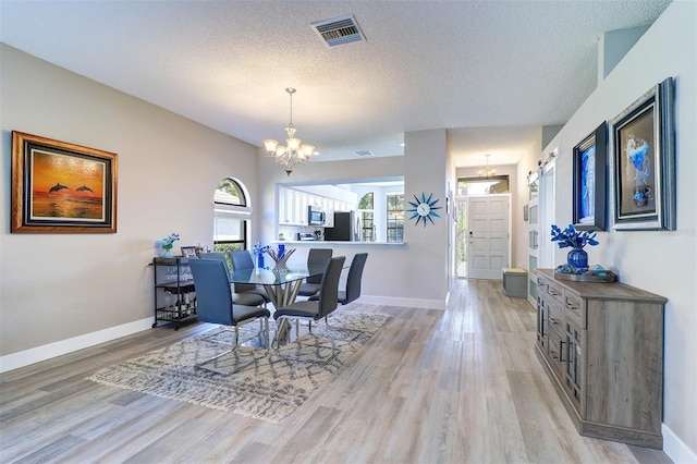 3704 Darston St, Palm Harbor, FL 34685 - dining room featuring light wood finished floors, a chandelier, and a textured ceiling