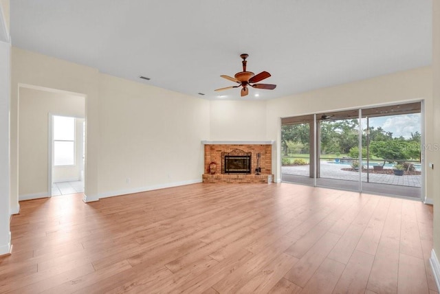 10510 Lithia Estates Dr, Lithia, FL 33547 - unfurnished living room featuring a ceiling fan, light wood finished floors, plenty of natural light, and a fireplace