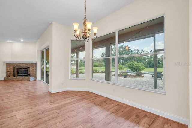 10510 Lithia Estates Dr, Lithia, FL 33547 - unfurnished dining area featuring a chandelier, wood finished floors, plenty of natural light, and a brick fireplace