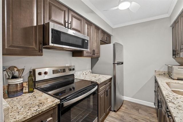 3325 Bayshore Blvd Unit A31, Tampa, FL 33629 - kitchen featuring stainless steel appliances, dark brown cabinets, ornamental molding, light wood-style flooring, and a ceiling fan