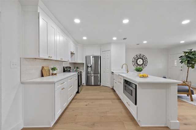 4753 58th St N, Kenneth City, FL 33709 - kitchen with stainless steel appliances, a peninsula, light wood finished floors, white cabinetry, and recessed lighting