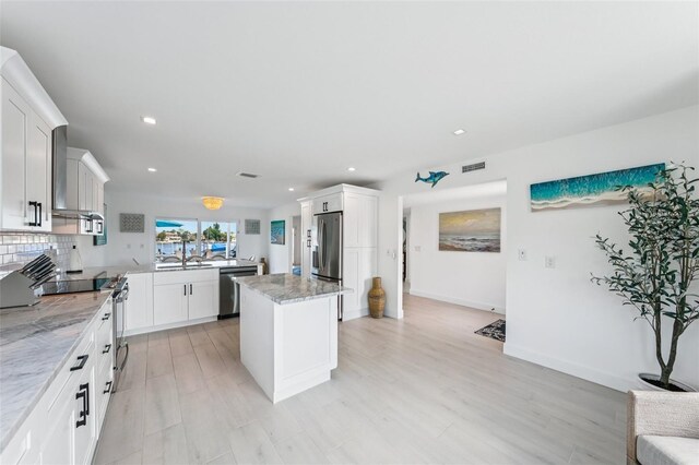 311 22nd St, Belleair Beach, FL 33786 - kitchen with stainless steel appliances, recessed lighting, a kitchen island, light stone countertops, and white cabinets
