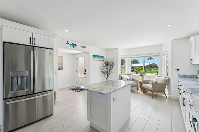 311 22nd St, Belleair Beach, FL 33786 - kitchen with stainless steel fridge with ice dispenser, light stone countertops, a center island, white cabinets, and recessed lighting