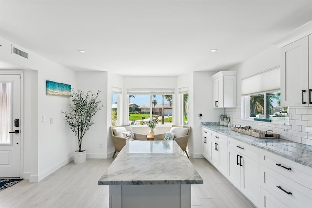 311 22nd St, Belleair Beach, FL 33786 - kitchen featuring decorative backsplash, light stone countertops, a center island, recessed lighting, and white cabinets
