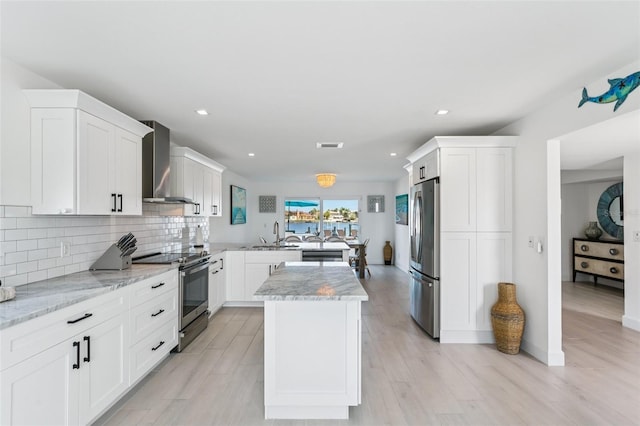 311 22nd St, Belleair Beach, FL 33786 - kitchen with appliances with stainless steel finishes, wall chimney exhaust hood, a peninsula, backsplash, and recessed lighting
