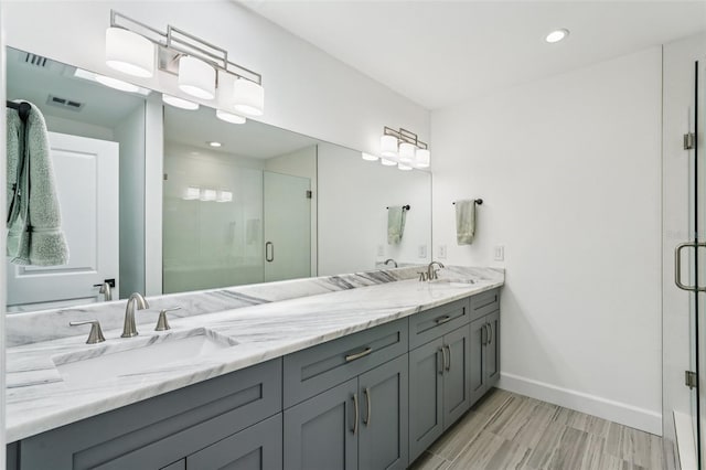 311 22nd St, Belleair Beach, FL 33786 - bathroom featuring double vanity, a shower stall, recessed lighting, and wood finished floors