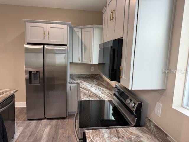 2404 Cassell St, Tampa, FL 33605 - kitchen featuring appliances with stainless steel finishes, light stone counters, light wood-style floors, and white cabinetry