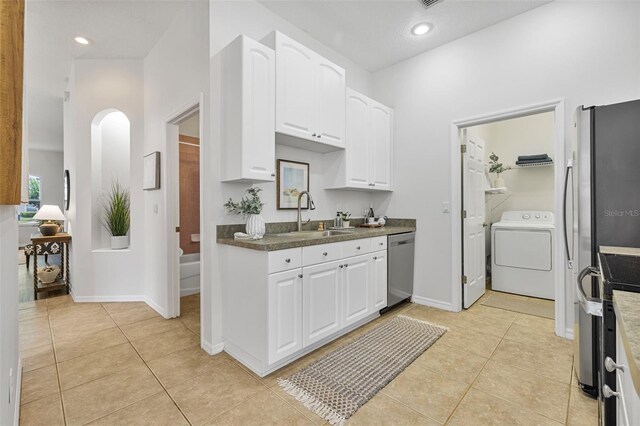 2537 Stanhope Dr, New Port Richey, FL 34655 - kitchen featuring washer / clothes dryer, stainless steel dishwasher, arched walkways, white cabinetry, and light tile patterned floors