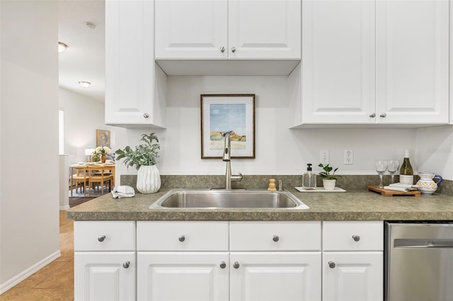 2537 Stanhope Dr, New Port Richey, FL 34655 - kitchen with stainless steel dishwasher, dark countertops, light tile patterned floors, and white cabinetry