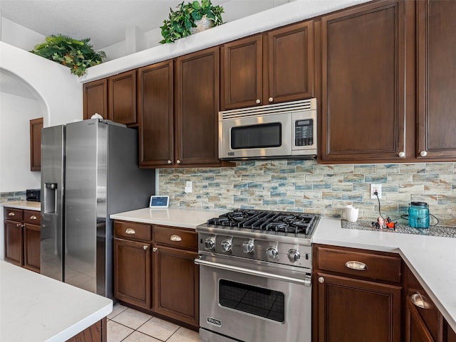12439 Bristol Commons Cir, Tampa, FL 33626 - kitchen featuring stainless steel appliances, light countertops, decorative backsplash, light tile patterned flooring, and arched walkways