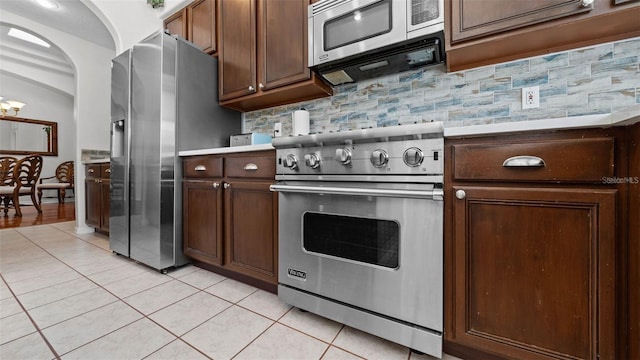 12439 Bristol Commons Cir, Tampa, FL 33626 - kitchen featuring appliances with stainless steel finishes, light tile patterned floors, backsplash, a chandelier, and dark brown cabinets