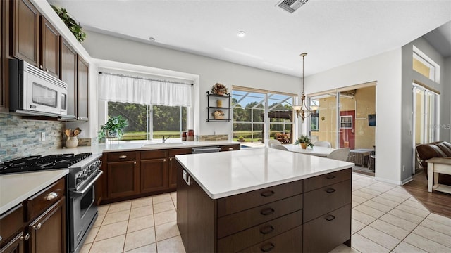 12439 Bristol Commons Cir, Tampa, FL 33626 - kitchen with appliances with stainless steel finishes, light tile patterned floors, light countertops, a center island, and recessed lighting