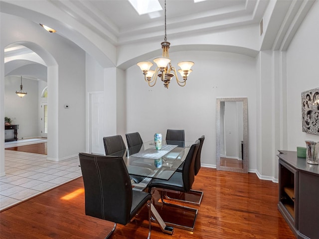 12439 Bristol Commons Cir, Tampa, FL 33626 - dining space featuring a chandelier, arched walkways, a towering ceiling, wood finished floors, and a skylight