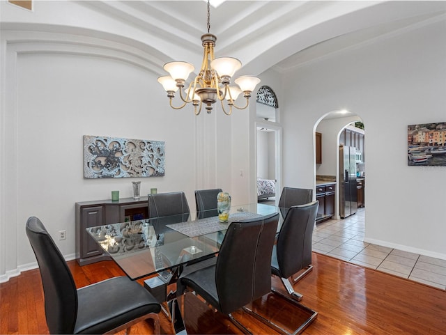 12439 Bristol Commons Cir, Tampa, FL 33626 - dining area with arched walkways, a chandelier, and light wood-style flooring