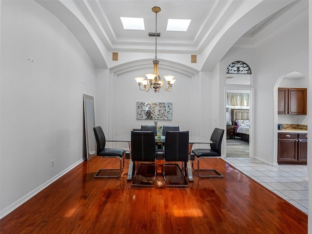 12439 Bristol Commons Cir, Tampa, FL 33626 - dining space with a raised ceiling, a chandelier, arched walkways, wood finished floors, and a towering ceiling