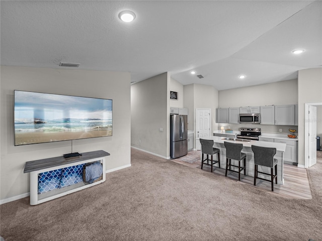 13105 Fruitville Way, Riverview, FL 33579 - kitchen featuring stainless steel appliances, light carpet, gray cabinets, a breakfast bar area, and vaulted ceiling