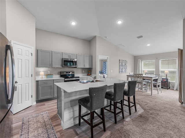 13105 Fruitville Way, Riverview, FL 33579 - kitchen featuring stainless steel appliances, gray cabinetry, vaulted ceiling, a kitchen island with sink, and a breakfast bar