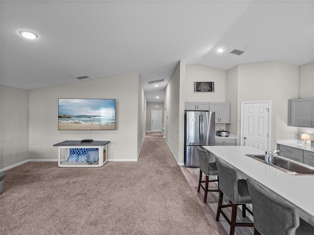 13105 Fruitville Way, Riverview, FL 33579 - kitchen featuring freestanding refrigerator, gray cabinetry, lofted ceiling, light colored carpet, and a breakfast bar area