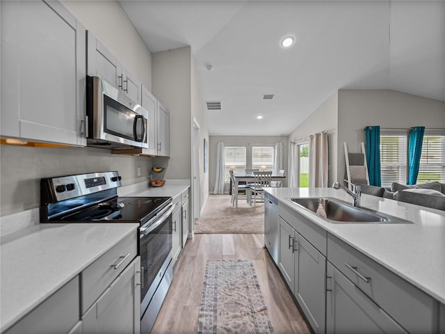 13105 Fruitville Way, Riverview, FL 33579 - kitchen with appliances with stainless steel finishes, gray cabinetry, light countertops, vaulted ceiling, and light wood-type flooring