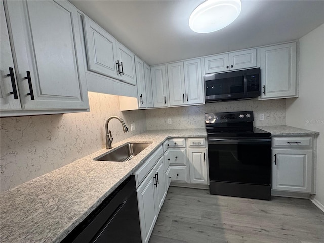 2459 Columbia Dr Unit 39, Clearwater, FL 33763 - kitchen with black appliances, light wood-style floors, white cabinetry, and tasteful backsplash