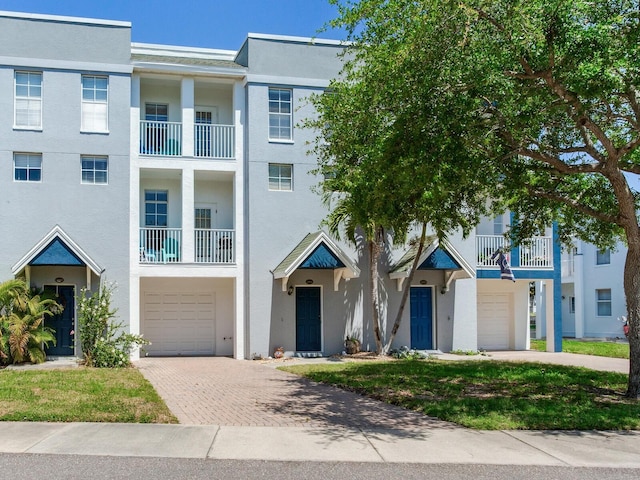 4503 Legacy Park Dr, Tampa, FL 33611 - view of front of property with a garage, decorative driveway, stucco siding, and a balcony