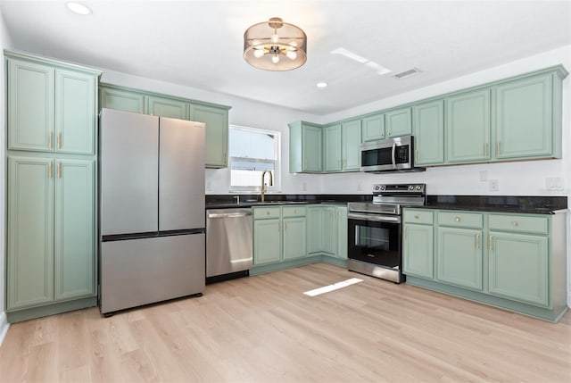 12106 Clearbrook Ct, Riverview, FL 33569 - kitchen with appliances with stainless steel finishes, green cabinets, light wood finished floors, dark countertops, and recessed lighting