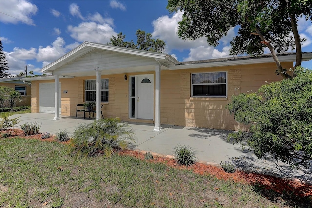 3707 Cambridge St, New Port Richey, FL 34652 - view of front of property with an attached garage, a porch, concrete block siding, and a front lawn