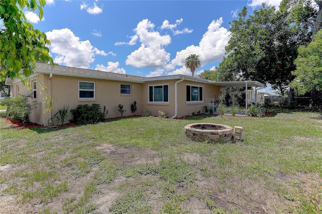 3707 Cambridge St, New Port Richey, FL 34652 - back of property with an outdoor fire pit, stucco siding, and a lawn