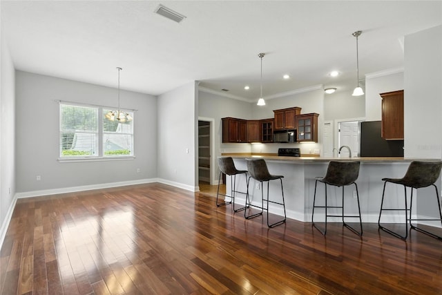 16609 NW 166th Dr, Alachua, FL 32615 - kitchen with black microwave, refrigerator, a kitchen bar, glass insert cabinets, and a peninsula