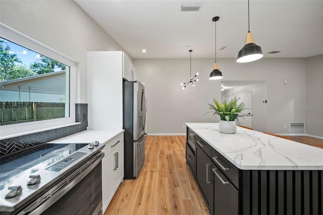 4639 Cabbage Palm Dr, Valrico, FL 33596 - kitchen with stainless steel appliances, a kitchen island, white cabinetry, dark cabinets, and decorative backsplash