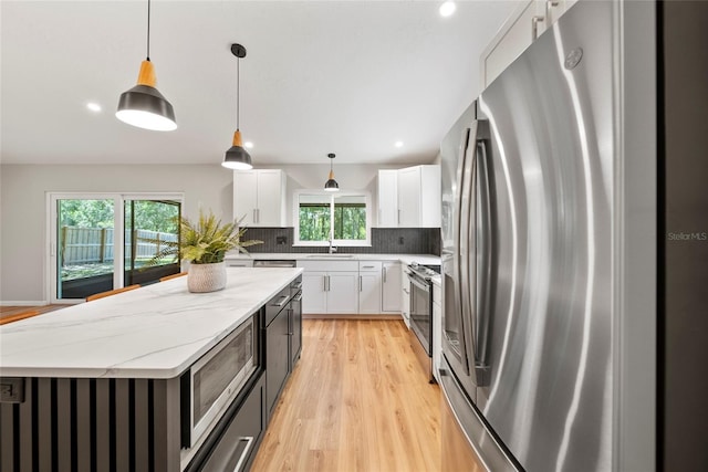 4639 Cabbage Palm Dr, Valrico, FL 33596 - kitchen with appliances with stainless steel finishes, a center island, backsplash, light wood finished floors, and light stone countertops