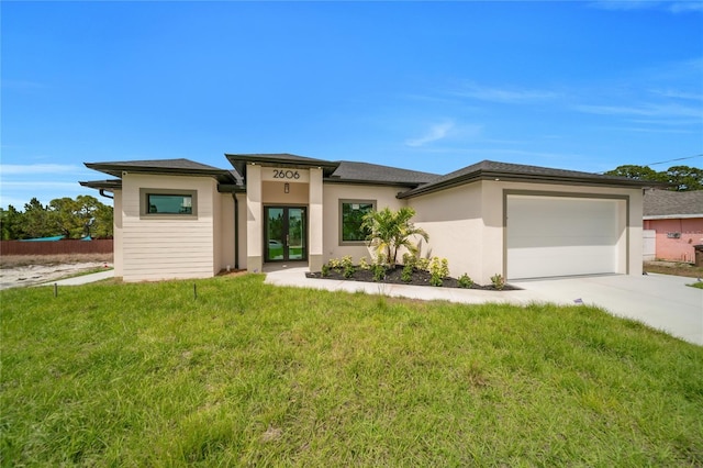 2606 34th St SW, Lehigh Acres, FL 33976 - prairie-style home with a garage, concrete driveway, a front lawn, stucco siding, and french doors