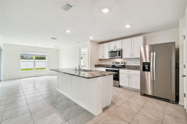4119 Autumn Amber Dr, Spring Hill, FL 34609 - kitchen with appliances with stainless steel finishes, dark stone counters, white cabinets, a center island with sink, and light tile patterned flooring