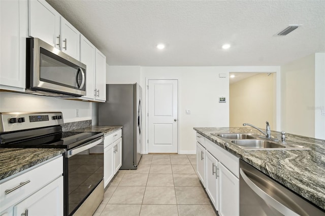 4119 Autumn Amber Dr, Spring Hill, FL 34609 - kitchen with stainless steel appliances, white cabinets, dark stone counters, light tile patterned flooring, and a textured ceiling