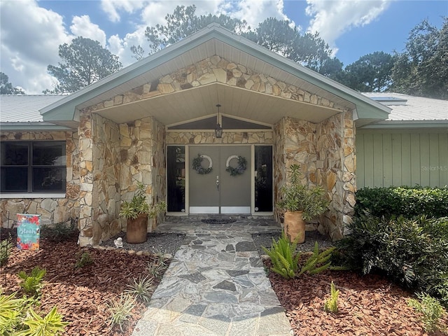 2215 Toniwood Ln, Palm Harbor, FL 34685 - view of exterior entry with stone siding and a metal roof