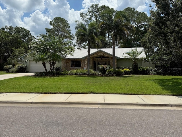 2215 Toniwood Ln, Palm Harbor, FL 34685 - ranch-style home featuring stone siding, an attached garage, a front yard, concrete driveway, and a metal roof