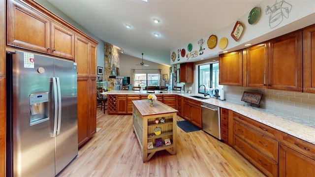 2215 Toniwood Ln, Palm Harbor, FL 34685 - kitchen featuring appliances with stainless steel finishes, a peninsula, light wood-type flooring, decorative backsplash, and brown cabinets