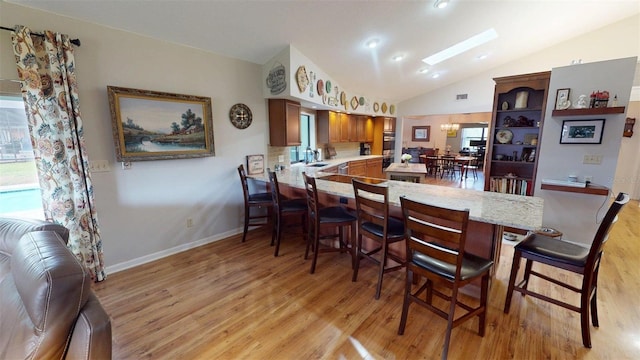 2215 Toniwood Ln, Palm Harbor, FL 34685 - dining space featuring light wood-style floors, lofted ceiling, and a skylight