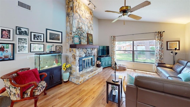 2215 Toniwood Ln, Palm Harbor, FL 34685 - living area with wood finished floors, a ceiling fan, a stone fireplace, and high vaulted ceiling