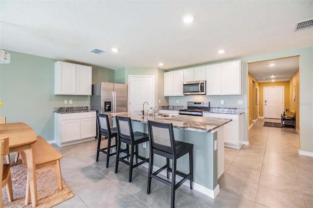 13304 Mylion Way, Spring Hill, FL 34610 - kitchen featuring stainless steel appliances, a kitchen breakfast bar, light stone counters, light tile patterned floors, and an island with sink