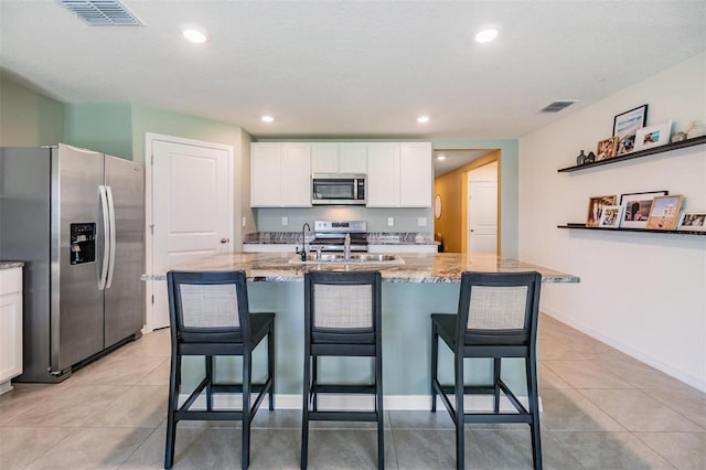 13304 Mylion Way, Spring Hill, FL 34610 - kitchen featuring appliances with stainless steel finishes, white cabinetry, light stone counters, a kitchen breakfast bar, and recessed lighting