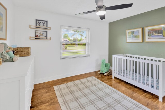 10811 Providence Oaks Dr, Riverview, FL 33578 - bedroom featuring a crib, a ceiling fan, and wood finished floors