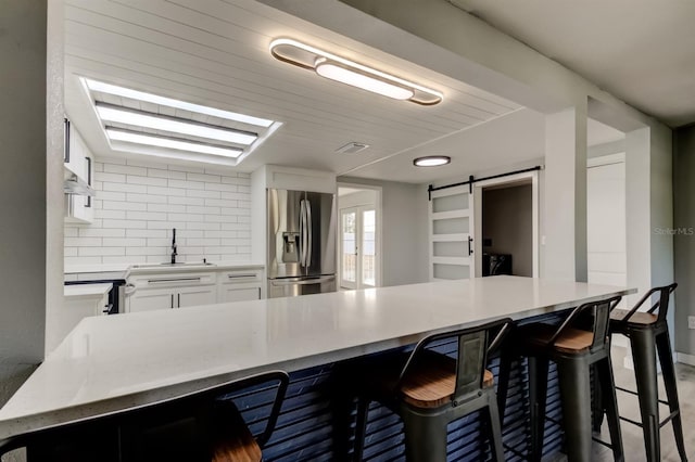 7031 Magnolia Valley Dr, New Port Richey, FL 34653 - kitchen with stainless steel refrigerator with ice dispenser, a barn door, a breakfast bar, and range hood